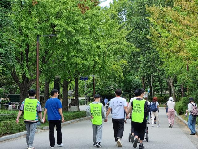 서울의 한 발달장애인 평생교육센터를 다니는 청년들과 교사들이 손을 잡고 공원을 산책하고 있다. 학령기가 지난 성인 발달장애인들은 갈 곳이 없다. 2017년 서울연구원 전수조사에 따르면, 성인 발달장애인의 40%는 낮 동안 집에만 머물렀다. 그나마 서울시는 25개 전 자치구(중구는 예정)에 평생교육센터 하나씩은 둔 상태지만, 부산시만 해도 올해 3월에야 첫 센터가 개소했다. 최나실 기자