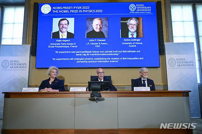 [스톡홀름(스웨덴)=AP/뉴시스]스웨덴 왕립과학원의 한스 엘레그렌 사무총장(가운데)과 노벨 물리학위원회의 에바 올슨(왼쪽), 토르스 한스 핸슨 위원이 4일 스톡홀름에서 2022년 노벨 물리학상 수상자를 발표하고 있다. 이들의 머리 위 화면에 알랭 아스펙트(프랑스), 존 클로저(미), 안톤 자일링거(오스트리아, 왼쪽부터) 등 공동수상자 3명의 사진이 보인다. 2022.10.4