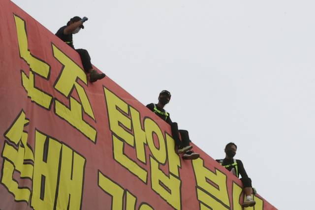 8월 18일 하이트진로에서 고공농성을 했던 화물노동자들이 노조원들의 격려에 호응하고 있다. 연합뉴스