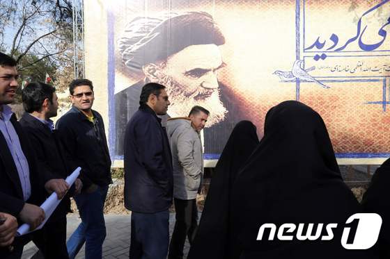이란 시민들이 1일 테헤란에서 이란 이슬람혁명의 아버지 아야톨라 루홀라 호메이니(1900∼1989)의 대형 초상화가 그려진 입간판 앞을 지나고 있다. 이란은 이슬람혁명 37주년을 맞아 이날부터 열흘 동안 축제를 벌인다. ⓒ AFP=뉴스1 ⓒ News1 최종일 기자