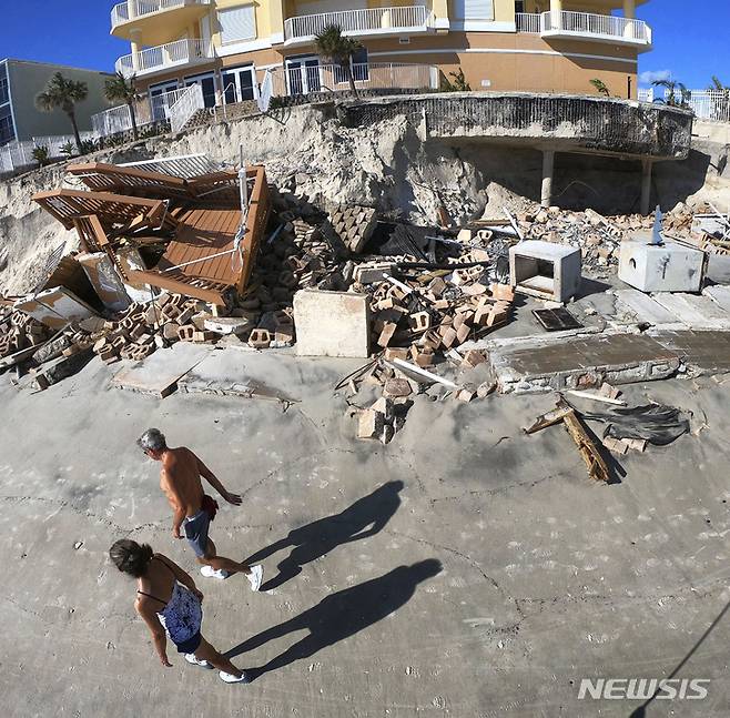 [데이토나비치쇼어스=AP/뉴시스] 3일(현지시간) 미 플로리다주 데이토나비치쇼어스에서 관광객들이 허리케인 이언으로 무너진 수영장 인근을 지나가고 있다. 플로리다에서 이언으로 인한 사망자가 1백 명을 넘어선 것으로 나타났으며 조 바이든 대통령이 5일 현장을 방문한다. 2022.10.04.