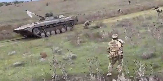 백기를 내걸고 우크라이나 군 진영으로 넘어온 러시아의 전투 차량 BMP-2. 우크라이나 병사에게 포위된 가운데 전투 차량 뒤로 러시아군 2명이 엎드리고 있다. 사진 인터넷 캡처