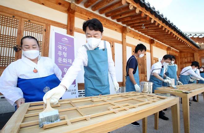 우범기 전주시장(왼쪽 두번째)이 지난 9월20일 서울 경복궁 흥복전에서 전주 한지를 바르면서 관객들에게 전주문화를 홍보하고 있다. 전주시 제공