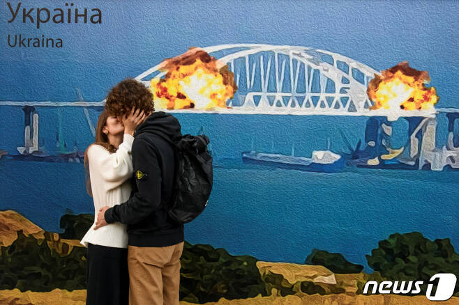 8일(현지시간) 우크라이나의 한 커플이 크름대교 폭발 기념 우표 도안 앞에서 키스를 하고 있다. ⓒ 로이터=뉴스1 ⓒ News1 박형기 기자