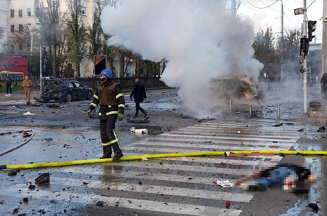 10일(현지시각) 아침 우크라이나 수도 키이우에 러시아군의 미사일 공격 때문으로 추정되는 폭발로 시민 한 사람이 숨져 쓰러져 있고 주변에서 연기가 치솟고 있다. 키이우/로이터 연합뉴스