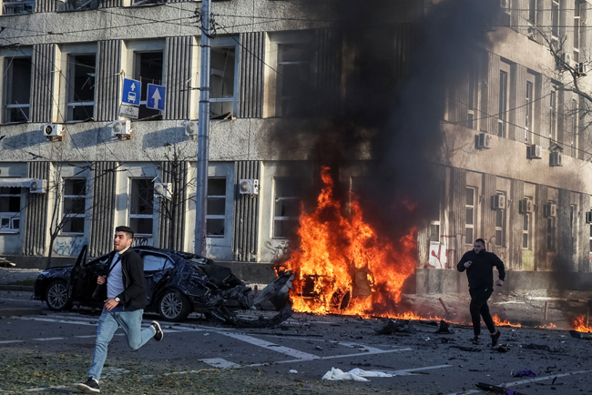 10일 오전 우크라이나 수도 키이우에서 러시아 공격으로 차량이 불타는 가운데 시민들이 대피하고 있다. 로이터 연합뉴스