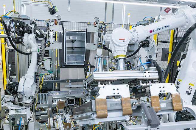 LG스마트파크 통합생산동 생산라인에 설치된 로봇팔이 20킬로그램(kg)이 넘는 커다란 냉장고 문을 가뿐히 들어 본체에 조립하는 모습.[LG전자 제공]