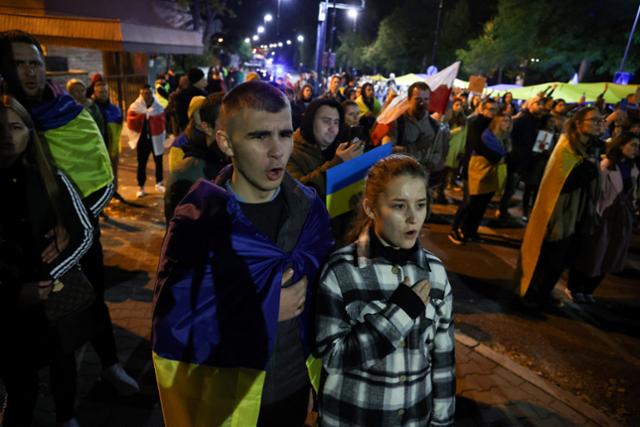 러시아의 우크라이나 폭격을 규탄하는 시위대가 10일 폴란드 바르샤바 러시아대사관 앞에서 시위 도중 우크라이나 국가를 부르고 있다. 바르샤바=로이터 연합뉴스