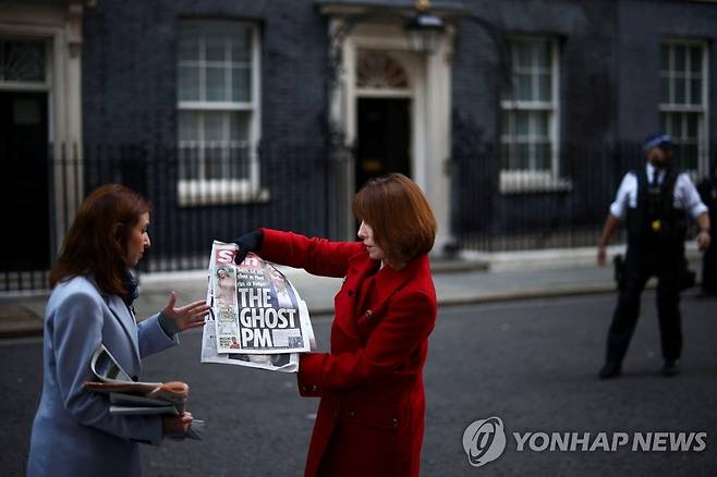 집권 6주 만에 흔들리는 트러스 영국 총리 (런던 로이터=연합뉴스) 18일(현지시간) 영국 런던의 총리집무실인 다우닝가 10번지 앞에서 TV리포터들이 이날 발간된 영국 일간 '더 선'(The Sun)을 들고 있다. 신문 1면에는 리즈 트러스 총리 사진과 함께 '유령 총리'(The Ghost PM)라는 표현이 있다. 트러스 총리는 지난달 보리스 존슨 전 총리의 뒤를 이어 취임했으나, 허술한 감세정책 등으로 지지율이 하락하며 정치적 위기를 겪고 있다. 2022.10.18 alo95@yna.co.kr