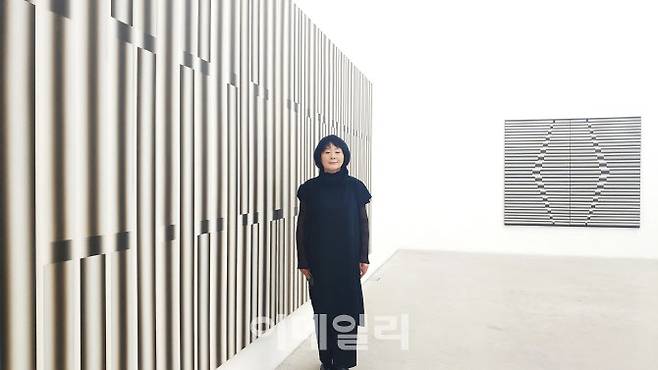 작가 이승조의 아내 고정자 여사가 서울 종로구 국제갤러리 ‘이승조 전’에 건 ‘핵 90-10, 90-11’(1986∼1990·229.5×699㎝) 옆에 섰다. 안성 스튜디오에서 마지막으로 작업한 미완성 대작으로 이번 전시작 중에서도 규모가 가장 크다. 뒤로 ‘핵’(1984·193.5×224)이 보인다(사진=오현주 문화전문기자).