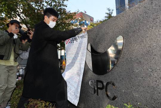 20일 서울 양재동 SPC 본사 앞에서 열린 평택 SPC 계열사 SPL의 제빵공장 사망 사고 희생자 서울 추모행사에서 성공회대 노학연대모임 가시 관계자가 대자보를 붙이고 있다. [연합뉴스]