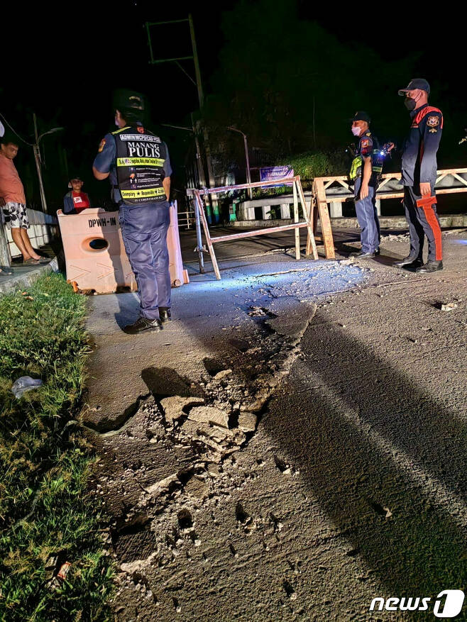 25일(현지시간) 필리핀 일로코스 노르테주에서 지진이 발생해 경찰관들이 균열로 폐쇄된 도로 위에서 경비를 서고 있다. ⓒ 로이터=뉴스1 ⓒ News1 권진영 기자
