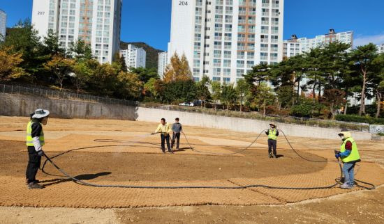 기장군 정관읍 관계자가 산책로 구간에 유채씨 파종을 마치고 살수차 호스를 이용해 물을 공급하고 있다.