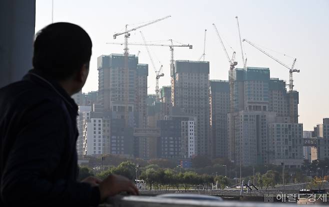 주택 시장의 침체와 레고랜드 채무불이행(디폴트) 사태에서 파생된 시중 단기 유동성 경색 후폭풍이 우량 사업장으로 꼽히는 한강변 재건축 단지에까지 직격탄을 날리고 있다. 이주비 대출이 거절되거나 금리가 급등하는 등 조합은 자금을 조달하느라 진땀을 빼고 있다. 27일 서울 서초구 잠수교에서 한 시민이 반포의 한 재건축 아파트 건설 현장을 바라보고 있다. 임세준 기자