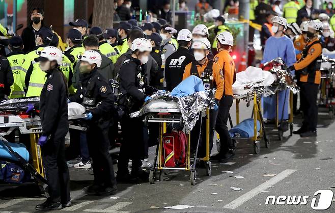 29일 밤 서울 용산구 이태원 한복판에서 심정지 환자가 대규모로 발생했다. 3년 만에 첫 '야외 노마스크' 핼러윈을 맞아 인파가 몰리면서 대규모 압사사고가 일어난 것으로 추정된다. 소방청은 이날 오후 11시13분 이태원에서 압사 추정 사고가 발생함에 따라 대응 3단계로 격상한다고 밝혔다. 사진은 20일 사고가 발생한 서울 용산구 이태원 사고현장에서 소방 관계자가 이동식 침대를 옮기는 모습. 2022.10.30/뉴스1 ⓒ News1 장수영 기자