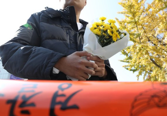 30일 오후 서울 용산구 이태원 압사 사고 현장에서 한 시민이 근조화를 들고 추모 공간 마련을 기다리고 있다. /뉴시스