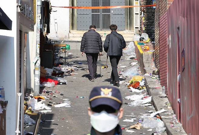 Investigators inspect the alleyway where the deadly stampede happened overnight in Itaewon, central Seoul, Sunday. (Yonhap)