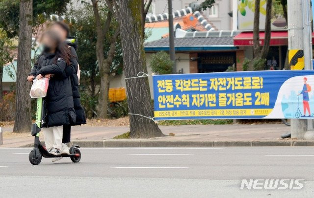 승차정원을 초과한 남녀가 헬멧도 쓰지 않고 전동킥보드를 타고 있다. 뉴시스