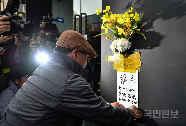 지난 29일 밤 서울 용산구 이태원로 일대에서 대규모 압사 참사가 발생한 가운데 30일 사고 현장을 찾은 시민이 희생자들을 애도하는 조화를 인근 상점 벽에 부착하고 있다. 이한결 기자