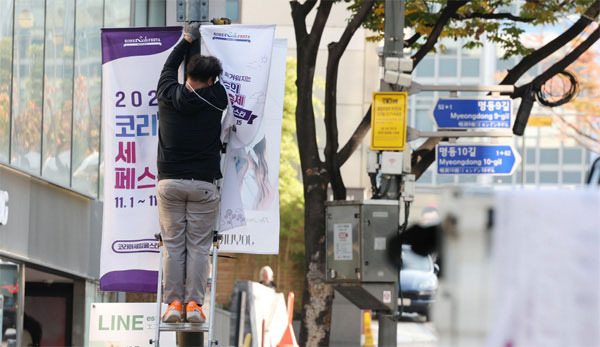 이태원 참사 희생자들을 추모하기 위해 `2022 코리아세일페스타` 개막식이 취소된 31일 서울 중구 명동에서 작업자가 홍보 현수막을 떼어내고 있다. [사진 출처 = 연합뉴스]