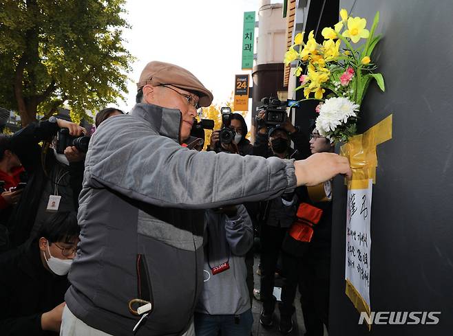 [서울=뉴시스] 김금보 기자 = 30일 오후 서울 용산구 이태원 할로윈 참사 현장 인근 건물 외벽에 한 시민이 근조화를 부착하고 애도하고 있다. 2022.10.30. kgb@newsis.com