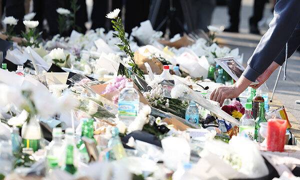 1일 서울 용산구 이태원 핼러윈데이 사고 추모공간을 찾은 외국인이 희생자로 보이는 여성의 사진을 국화꽃 사이에 내려놓고 있다. 연합뉴스