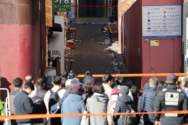 지난 4일 서울 용산구 이태원역 1번 출구 앞 참사 추모 공간을 찾은 시민들이 사고 현장을 보고 있다. 연합뉴스