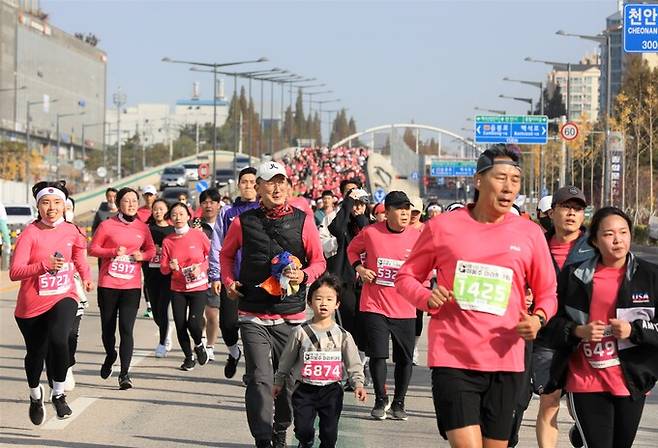 가족단위 시민 참가자들이 많은 대회에서 불당대로를 달리는 주자들.&nbsp;