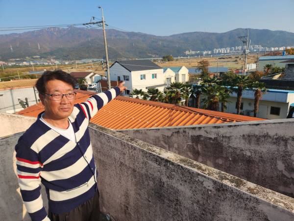 박한일 월촌마을 비상대책위원장이 8일 대동면 월촌 마을회관 옥상에서 마을 너머 빈 부지에 들어설 물류창고 건립 예정지 2곳 중 1 곳을 가리키고 있다. 박동필 기자