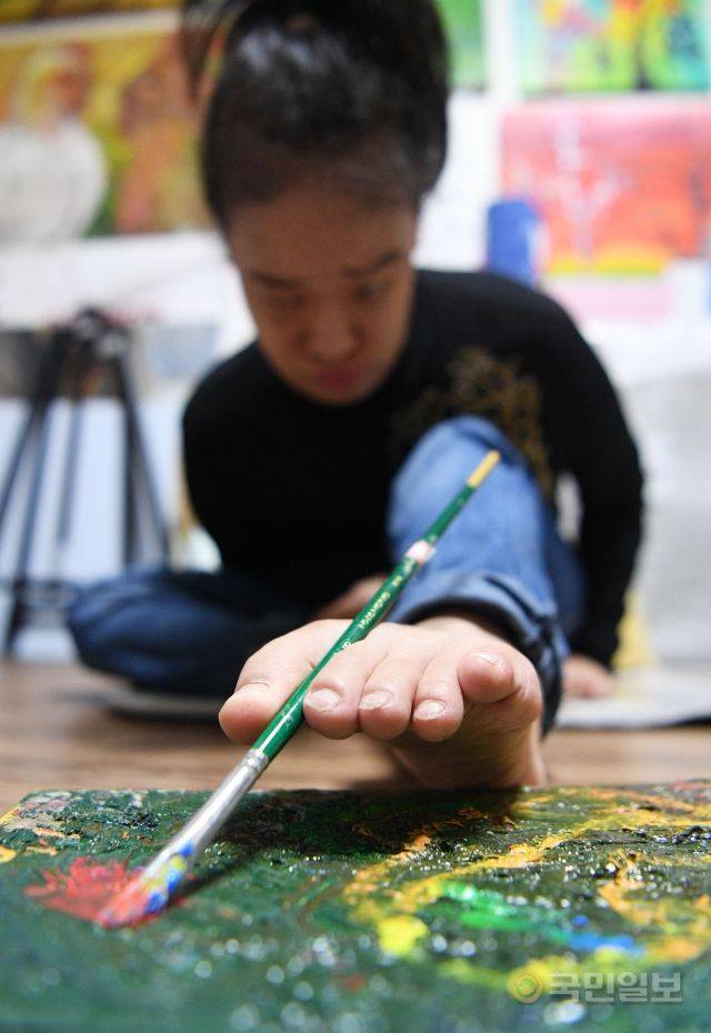 족필화가 이윤정 작가가 지난달 22일 서울 노원구 작업실에서 손대신 발로 붓을 놀리고 있다.