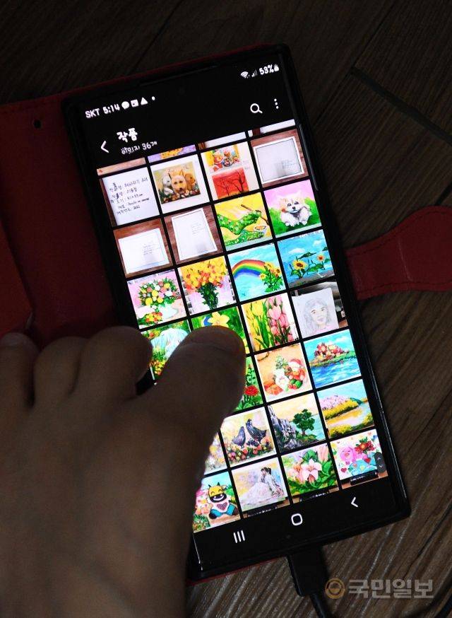 이윤정 작가가 지난달 22일 서울 노원구 작업실에서 작업한 그림을 사진으로 보여주고 있다.