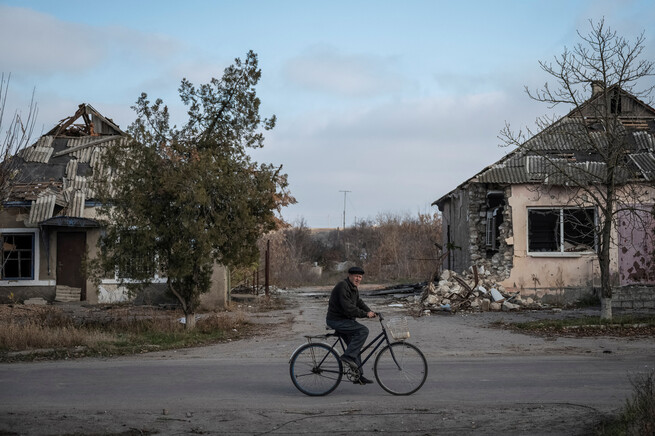 우크라이나 주민이 8일(현지시각) 남부 헤르손의 아르칸헬스케 마을에서 부서진 집 사이를자전거 타고 가고 있다. 로이터/연합뉴스