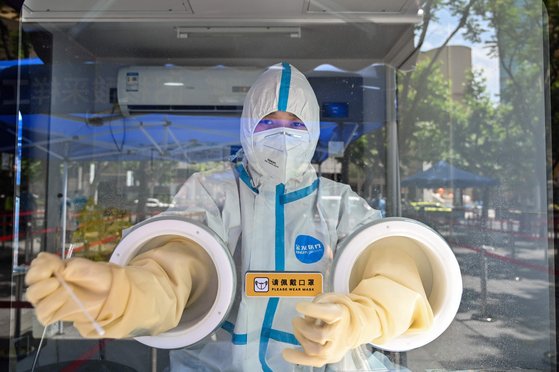 베이징 시내에 위치한 PCR 검사장. 방역요원이 부스 안에서 장갑을 낀 손만 내민 채 면봉 검사를 실시한다. [AP=연합]