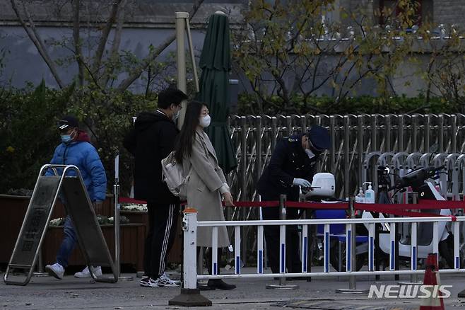 [베이징=AP/뉴시스]16일 중국 수도 베이징의 베이징대학 입구에서 방문객이 경비원의 검문을 받고 있다. 2022.11.16