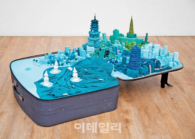 인슈전의 ‘휴대용 도시: 항저우’(Portable City: Hangzhou· 2011). 개인물품과 공공장소에 ‘기억’이란 카테고리를 결합해 세계화 이슈를 건드려온 연작 ‘휴대용 도시’ 중 한 점. 작가가 방문한 세계의 도시들에서 수집한 옷가지로 도시모형을 만들고 캐리어 안에 다시 배치하는 식으로 그간 43개의 여행가방을 제작했다. 여행가방·옷·돋보기·지도, 64×150×88㎝, ⓒ인슈전·페이스갤러리 제공.