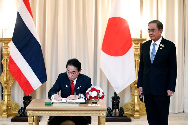 아시아태평양경제협력체(APEC) 정상회의에 참석하기 위해 태국 방콕을 방문한 기시다 후미오 일본 총리가 17일(현지시간) 쁘라윳 찬오차 태국 총리를 만나 방명록에 서명하고 있다. 방콕|AP연합뉴스