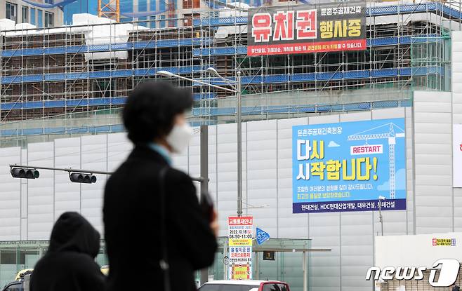 (서울=뉴스1) 박지혜 기자 = 16일 서울 강동구 둔촌주공 재건축 현장에 공사 재개를 알리는 현수막이 붙어 있다.  6개월간 멈춰섰던 둔촌주공아파트 재건축 사업이 오는 17일부터 다시 시작된다. 2022.10.16/뉴스1  Copyright (C) 뉴스1. All rights reserved. 무단 전재 및 재배포 금지.