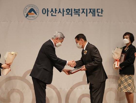 구두수선공 김병록씨(오른쪽)가 지난 17일 정진규 아산사회복지재단 이사(왼쪽)로부터 제34회 아산상 ‘자원봉사상’을 받고 있다. 사진 아산사회복지재단