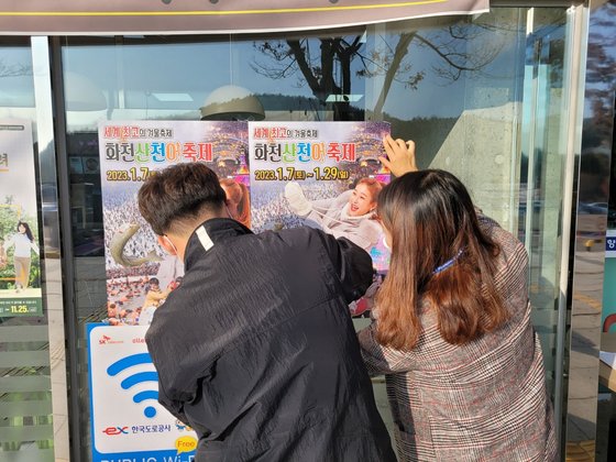 지난 17일 오후 강원 화천군 공무원들이 중앙고속도로 춘천휴게소 입구에 화천산천어축제 포스터를 붙이고 있는 모습. 사진 화천군