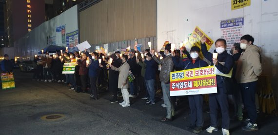 한국주식투자자연합회가 지난 13일 서울 여의도 민주당사 앞에서 금융투자소득세 도입에 반대하는 촛불시위를 하고 있다. /한투연 제공