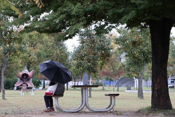 23일인 수요일은 아침 최저기온이 6도까지 떨어지며 일부 지역엔 최대 100㎜ 이상의 비가 내릴 전망이다. 사진은 지난달 9일 서울 영등포구 여의도 한강공원에서 우산을 쓴 채 벤치에 앉아 있는 시민. /사진=뉴스1