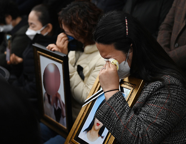 이태원 참사 유가족들이 22일 오전 서울 서초구 민주사회를 위한 변호사모임 대회의실에서 열린 입장발표 기자회견에서 자식의 영정사진을 품에 안고 눈물을 흘리고 있다. 뉴시스