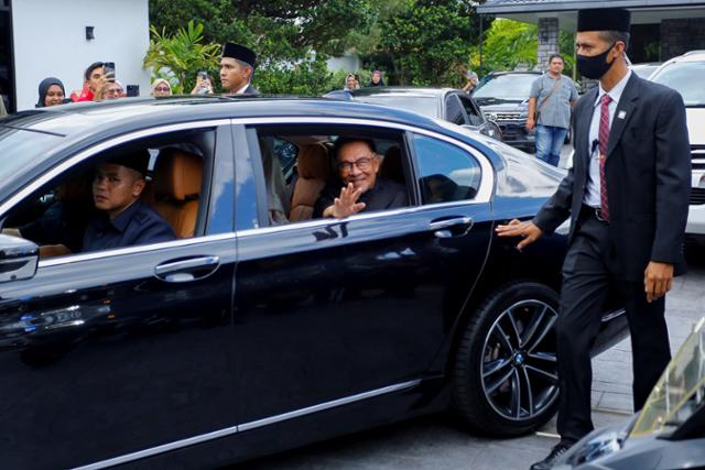 말레이시아 신임 총리로 지명된 희망연대(PH) 수장 안와르 이브라힘 전 부총리가 24일 카장의 자택을 나서면서 지지자들에게 손을 흔들고 있다. 카장=로이터 연합뉴스