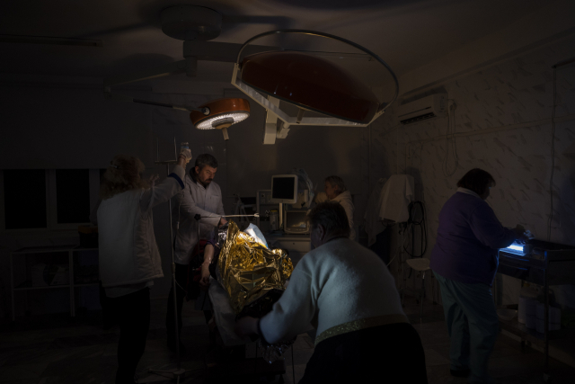 러시아군 폭격으로 우크라이나 전력시설이 상당 부분 파괴된 가운데 22일(현지시간) 남부 헤르손의 한 병원 의사들이 어두운 수술실에서 러시아군 공격에 부상당한 13세 남자 어린이의 왼쪽 팔 절단 수술을 하고 있다. 우크라이나 의사들은 물과 전기, 수술장비가 부족해 치료에 어려움을 겪고 있다. 러시아군은 지난 11일 헤르손에서 철수했지만 이 지역에 계속 공격을 퍼붓고 있다./연합뉴스