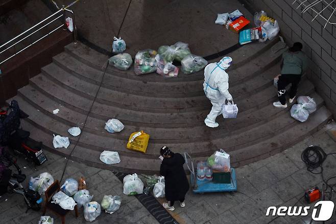 24일 중국 수도 베이징에서 방역복을 입은 노동자가 봉쇄된 건물에서 배달 물품을 옮기고 있다. 2022,11.24 ⓒ 로이터=뉴스1 ⓒ News1 김정률 기자