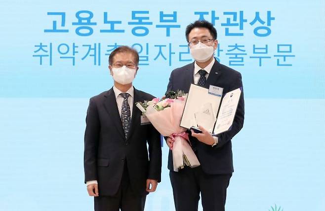 LIG넥스원 전인석 인사지원실장과 고용노동부 이정식 장관이 상패와 상장을 전달 후 기념촬영을 하고 있다.