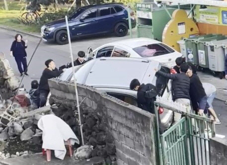 24일 제주 서귀포시 동홍동 사고 현장에서 시민들이 사고 차량을 들어올리고 있다. [독자 제공]
