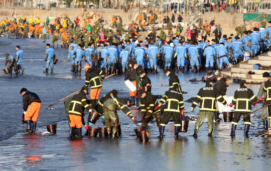 2007년 12월 충남 태안 앞바다 기름유출 사고 당시 민관이 힘을 모아 해변으로 몰려든 기름 제거 작업을 하고 있다.                                                                                          사진=충남도 제공