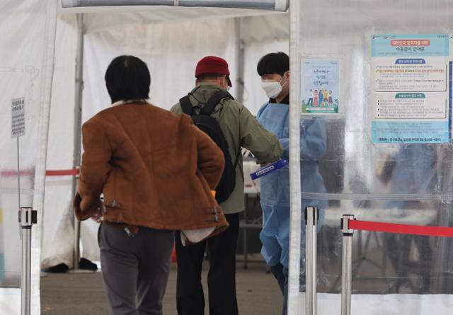 코로나19 신규 확진자 수가 4만7,028명을 기록한 27일 서울역 코로나19 임시선별검사소를 찾은 시민들이 의료진의 안내를 받고 있다. 연합뉴스