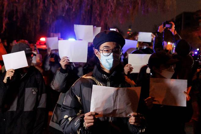 지난 27일 중국 베이징에서 열린 우루무치 화재 희생자 추도식에서 코로나19 봉쇄 조치에 반대하는 시민들이 검열에 대한 저항의 상징으로 ‘백지 시위’를 펼치고 있다. (사진=연합뉴스)